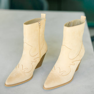 Beige cowboy boots on a gray surface with a blurred background