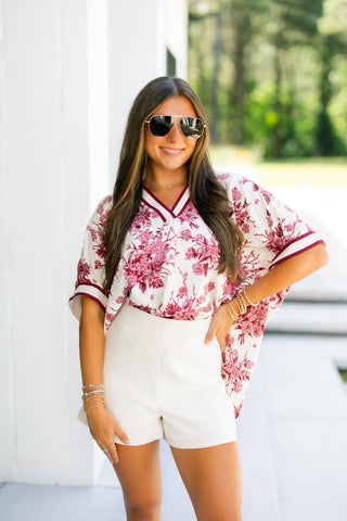 Woman wearing a floral blouse and white shorts outdoors
