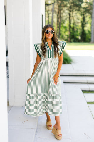 Woman wearing a green and white striped midi dress with sunglasses outdoors.