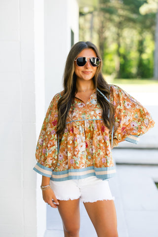 Woman wearing a floral blouse and sunglasses outdoors