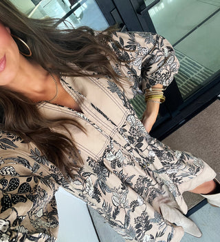 Woman wearing a taupe and black floral shift dress.
